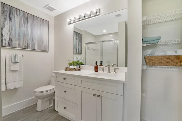 a bathroom with a toilet a sink a mirror a vanity and shower