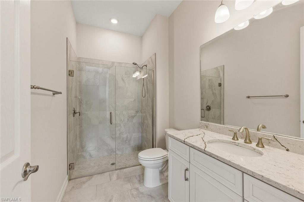 28053 Captiva Shell Loop Bonita Springs, FL 34135 - Photo 25 of 50 a bathroom with a granite countertop sink toilet a large mirror a shower and vanity