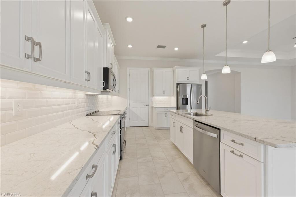 28053 Captiva Shell Loop Bonita Springs, FL 34135 - Photo 9 of 50 a large kitchen with stainless steel appliances kitchen island a large counter top a sink a stove and a refrigerator