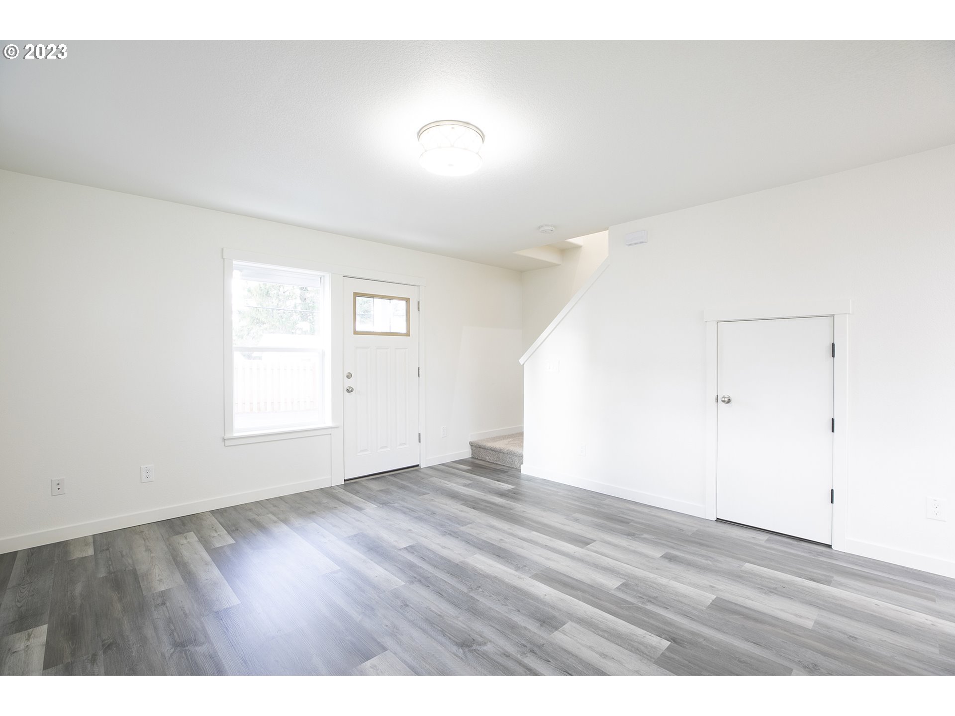 9046 Southeast Clinton Street, Unit B Portland, OR 97266 - Photo 5 of 18 a view of an empty room with wooden floor and a window