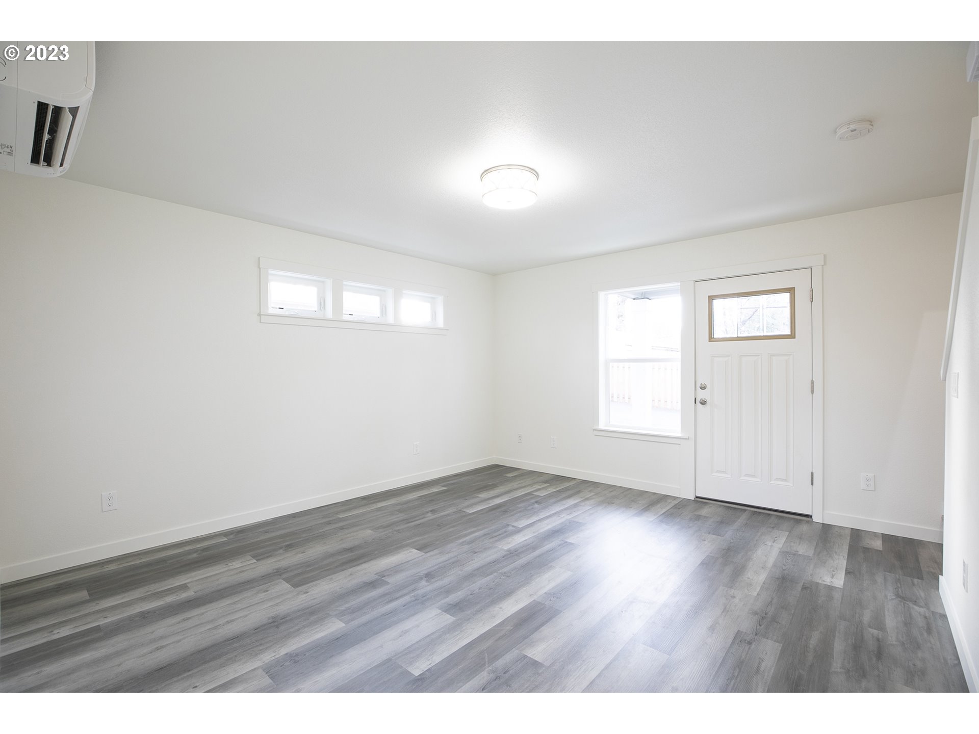 9046 Southeast Clinton Street, Unit B Portland, OR 97266 - Photo 6 of 18 an empty room with wooden floor and windows