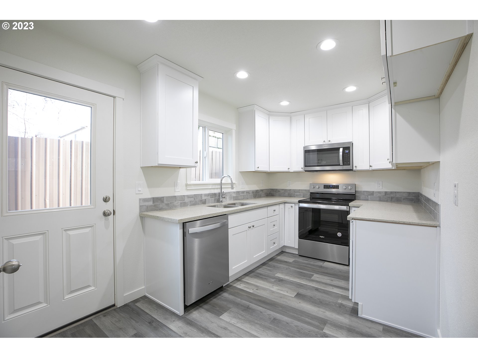 9046 Southeast Clinton Street, Unit B Portland, OR 97266 - Photo 7 of 18 a kitchen with stainless steel appliances granite countertop a stove a sink and a microwave