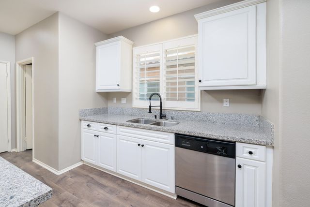 a kitchen with granite countertop white cabinets and a sink