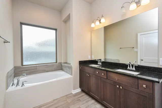 a bathroom with a granite countertop bathtub a sink and mirror