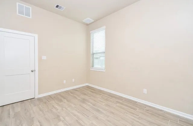 an empty room with wooden floor and windows