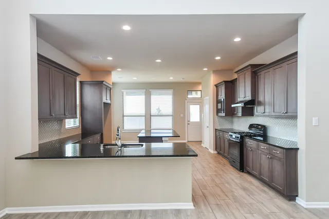 a kitchen with stainless steel appliances granite countertop a sink stove and refrigerator