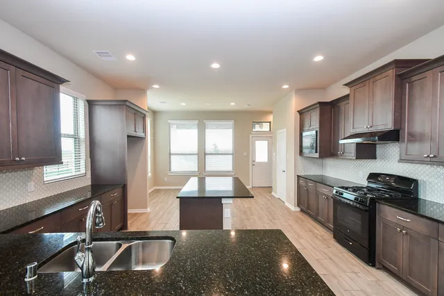 a kitchen with stainless steel appliances granite countertop a sink stove and refrigerator