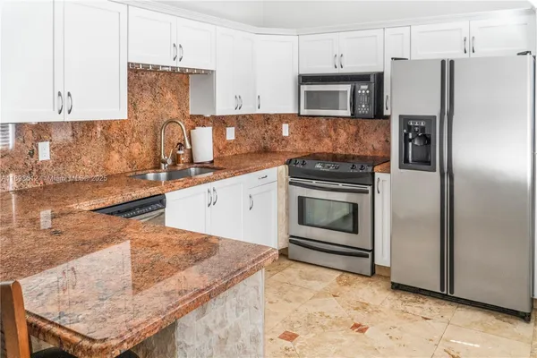 a kitchen with granite countertop a stove top oven and refrigerator