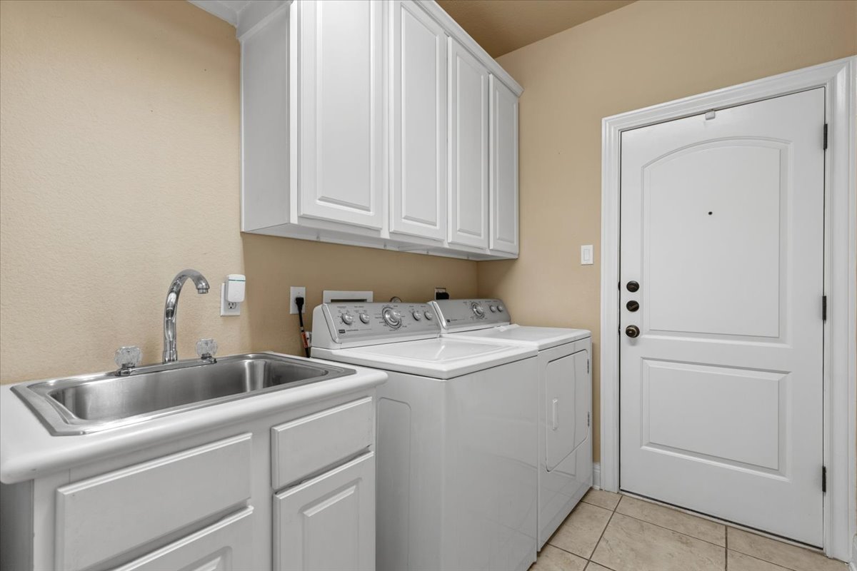 111 Whitley Drive Austin, TX 78738 - Photo 33 of 38 Laundry room downstairs off the single garage, with cabinet space, with washer and dryer, 2nd fridge, and pull down ironing board.