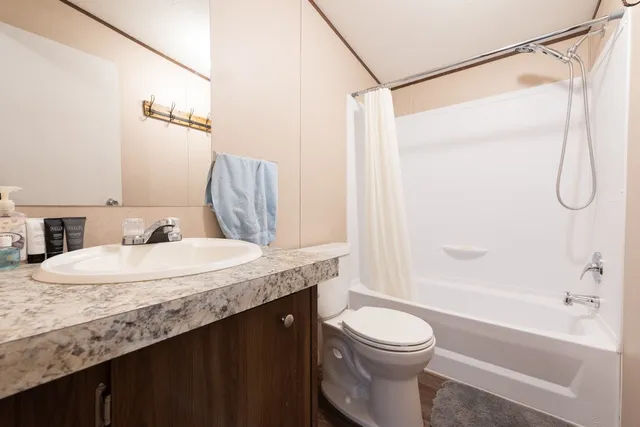 a bathroom with a granite countertop sink toilet and shower