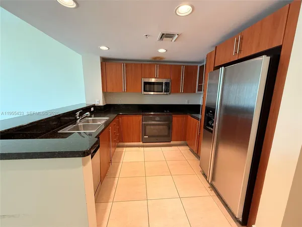 a kitchen with stainless steel appliances granite countertop a refrigerator a stove and a sink