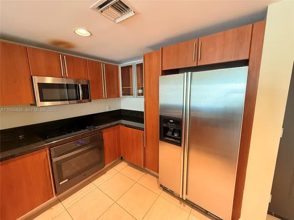 a kitchen with granite countertop cabinets stainless steel appliances and a microwave