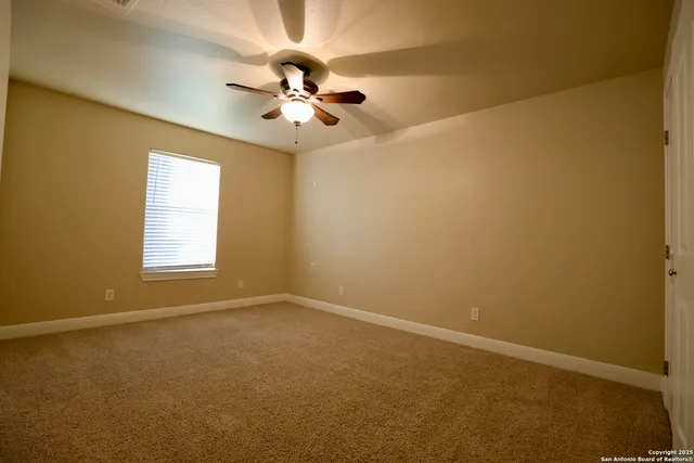 an empty room with a window and a fan