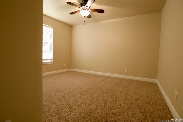 an empty room with a window and a fan