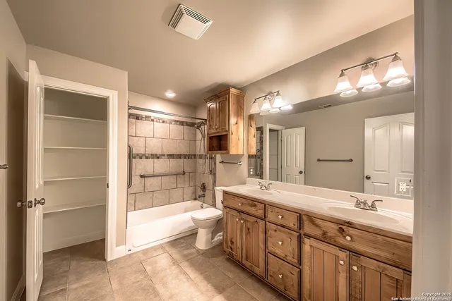 a bathroom with a double vanity sink a large mirror and a bathtub