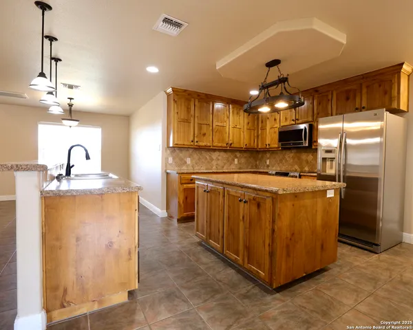 a kitchen with stainless steel appliances granite countertop a refrigerator and a sink