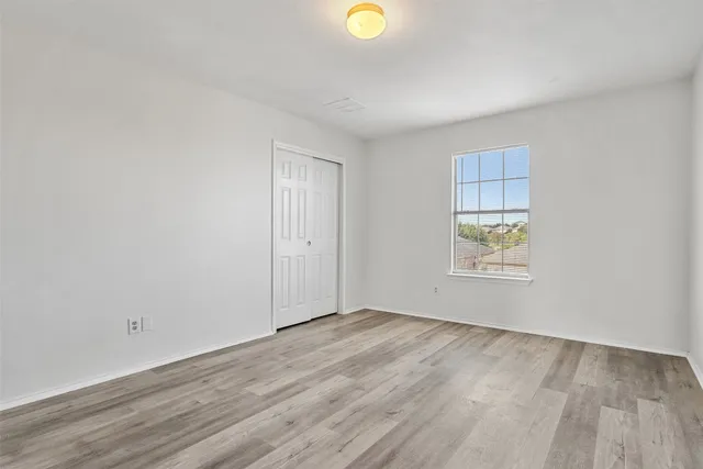a view of an empty room with window and wooden floor