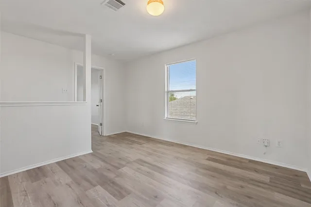 a view of an empty room with wooden floor and window