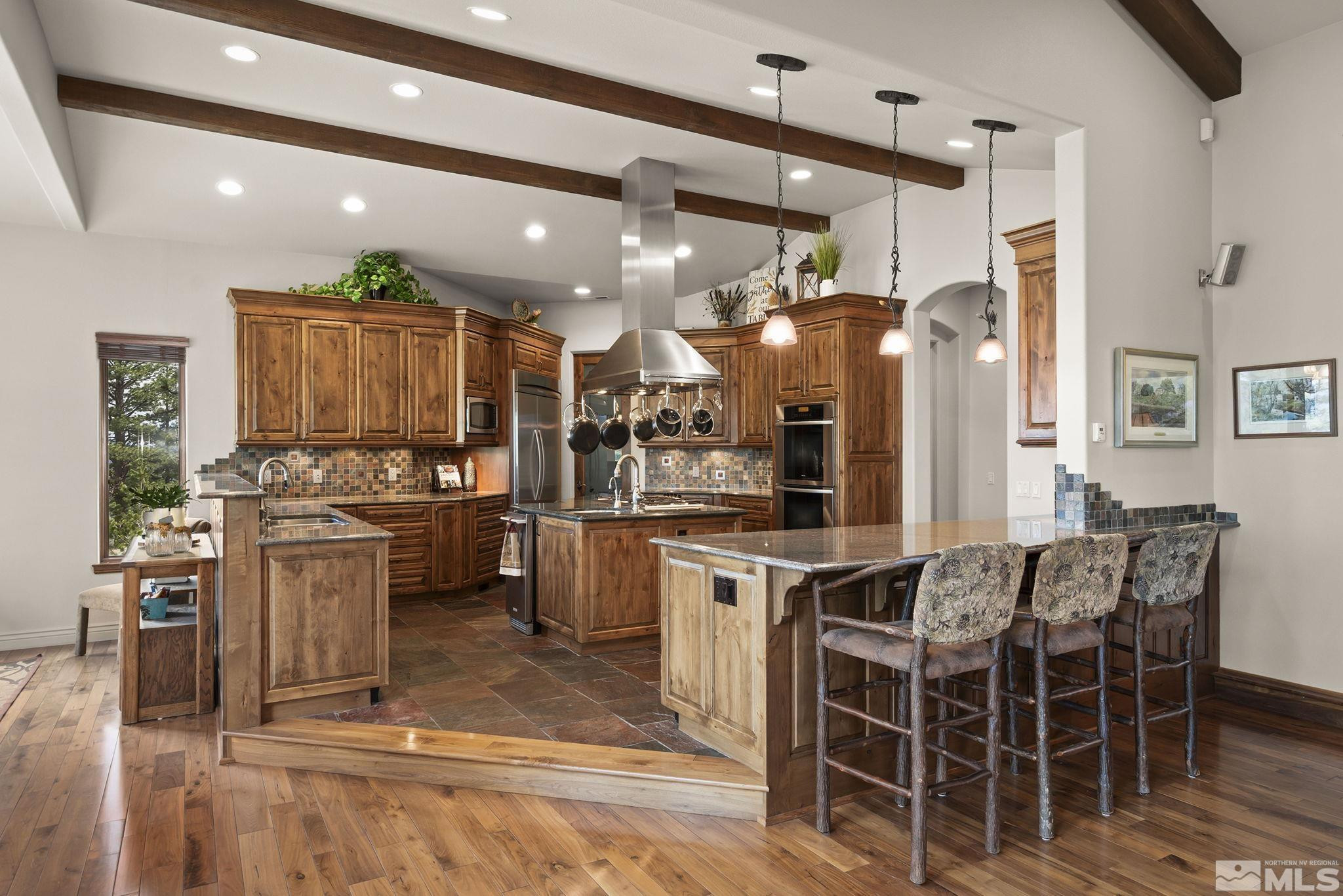 4660 West Pinewild Road Reno, NV 89511 - Photo 9 of 40 a kitchen with stainless steel appliances kitchen island granite countertop a table chairs sink and cabinets
