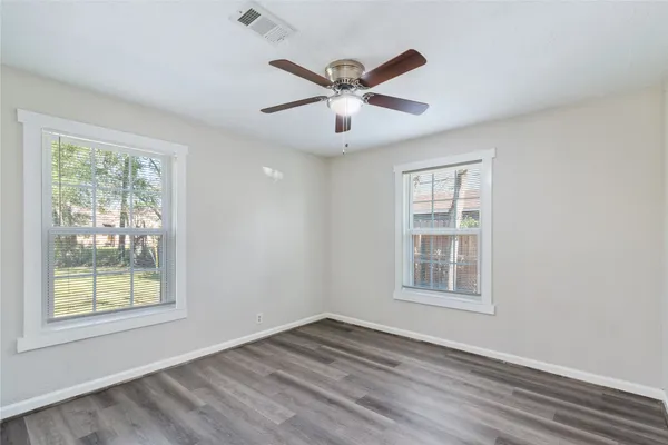 a view of empty room with wooden floor and fan