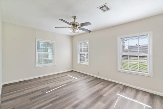 a view of an empty room with a window and a ceiling fan