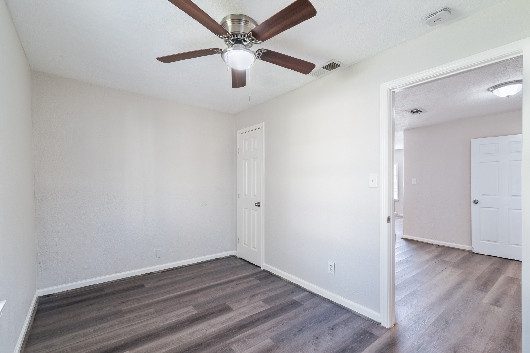 5825 Southurst Street Houston, TX 77033 - Photo 9 of 23 an empty room with wooden floor and a ceiling fan