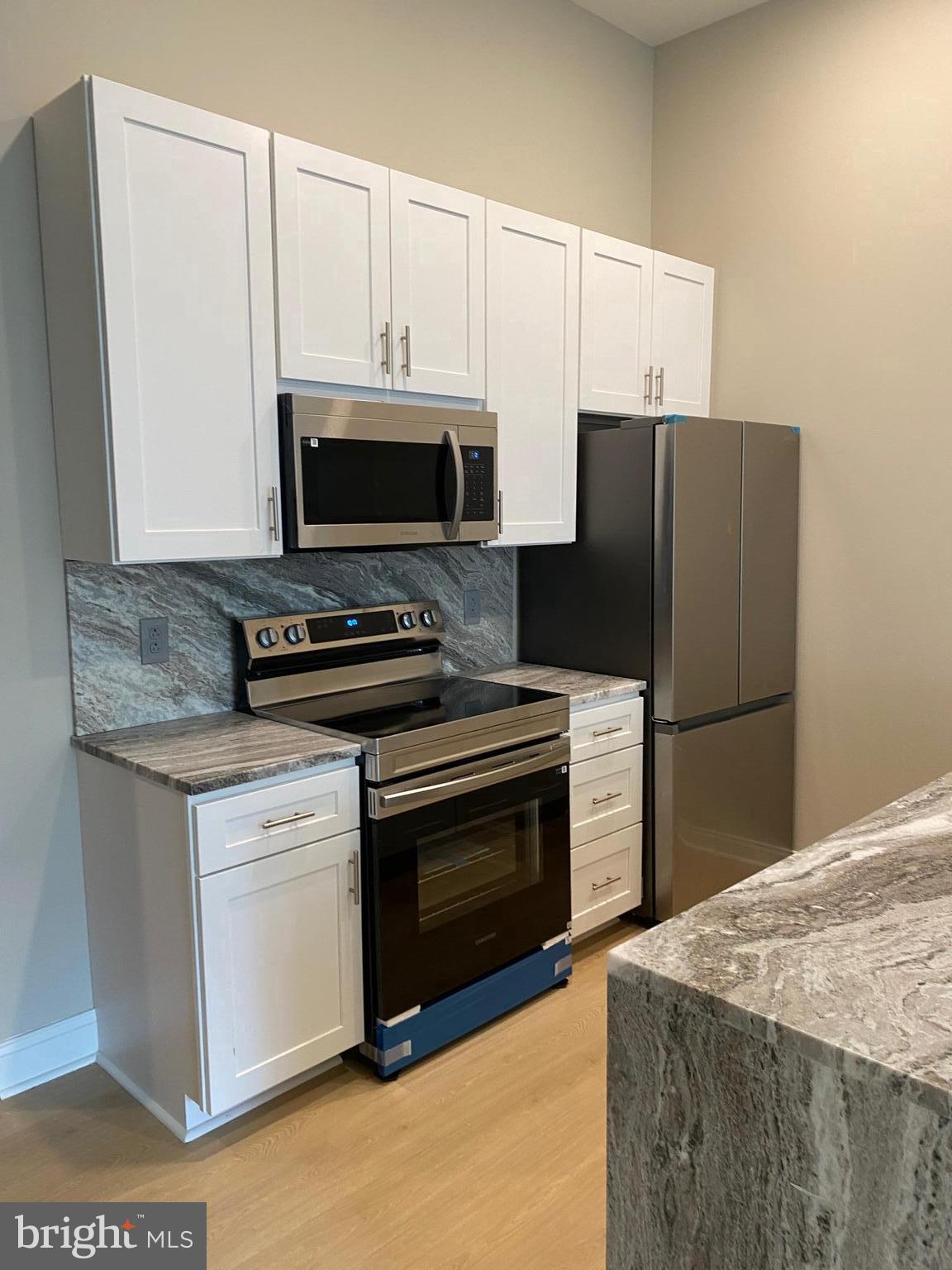 1900-20 Arch Street, Unit 109 Philadelphia, PA 19103 - Photo 2 of 34 a kitchen with granite countertop a refrigerator stove and microwave