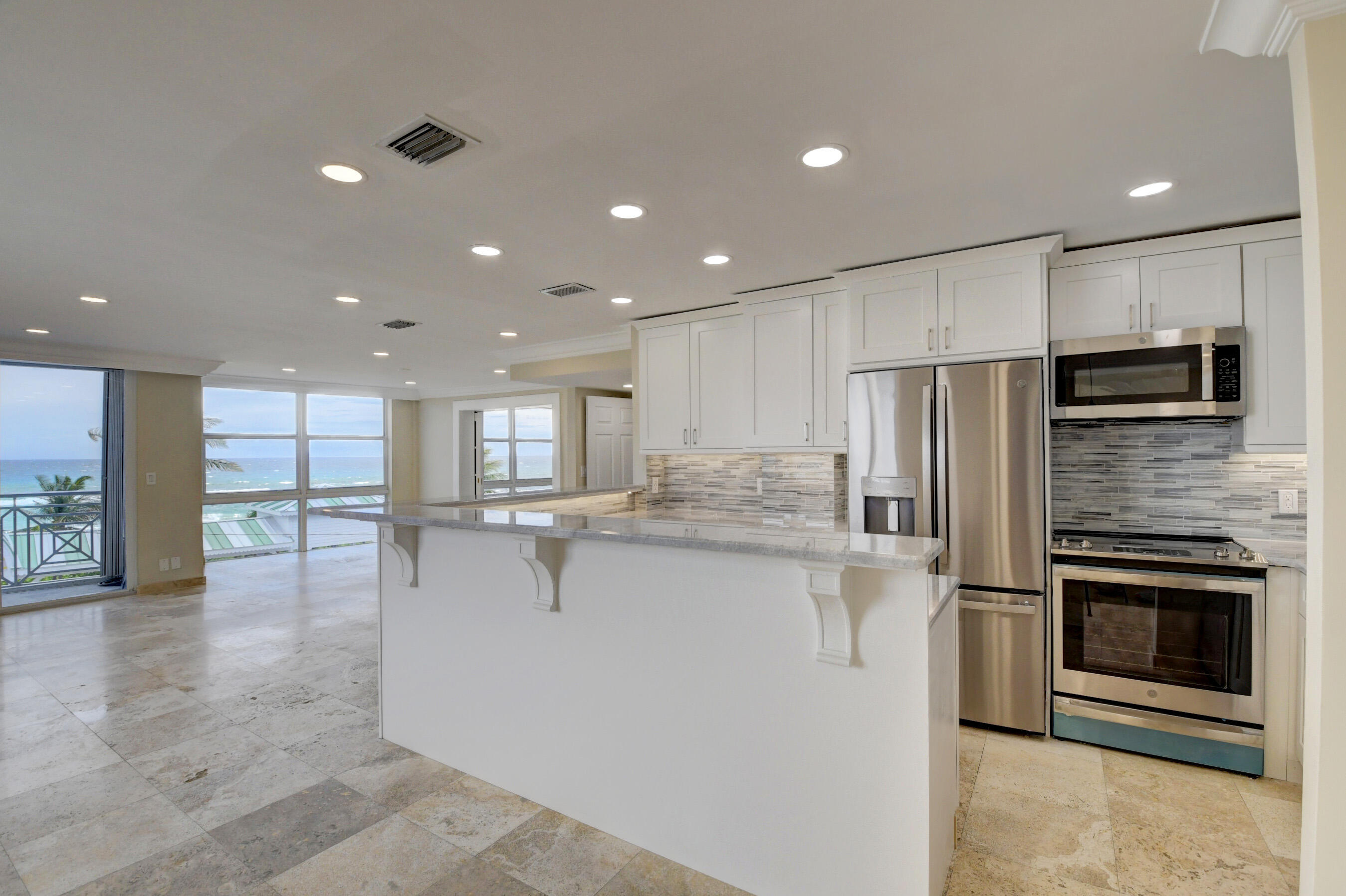 36 South Ocean Boulevard, Unit B3 Delray Beach, FL 33483 - Photo 12 of 47 a large kitchen with stainless steel appliances kitchen island granite countertop a refrigerator and a stove top oven
