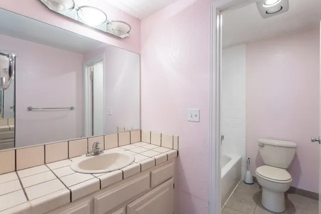 a bathroom with a granite countertop sink a toilet a mirror and shower