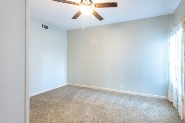 an empty room with a window and a ceiling fan