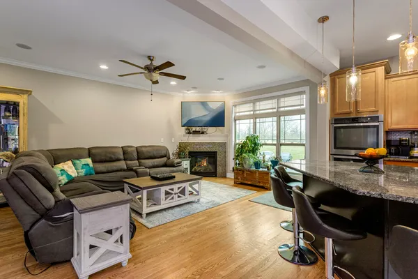 a kitchen with stainless steel appliances granite countertop a refrigerator a sink dishwasher a stove a dining table and chairs with wooden floor