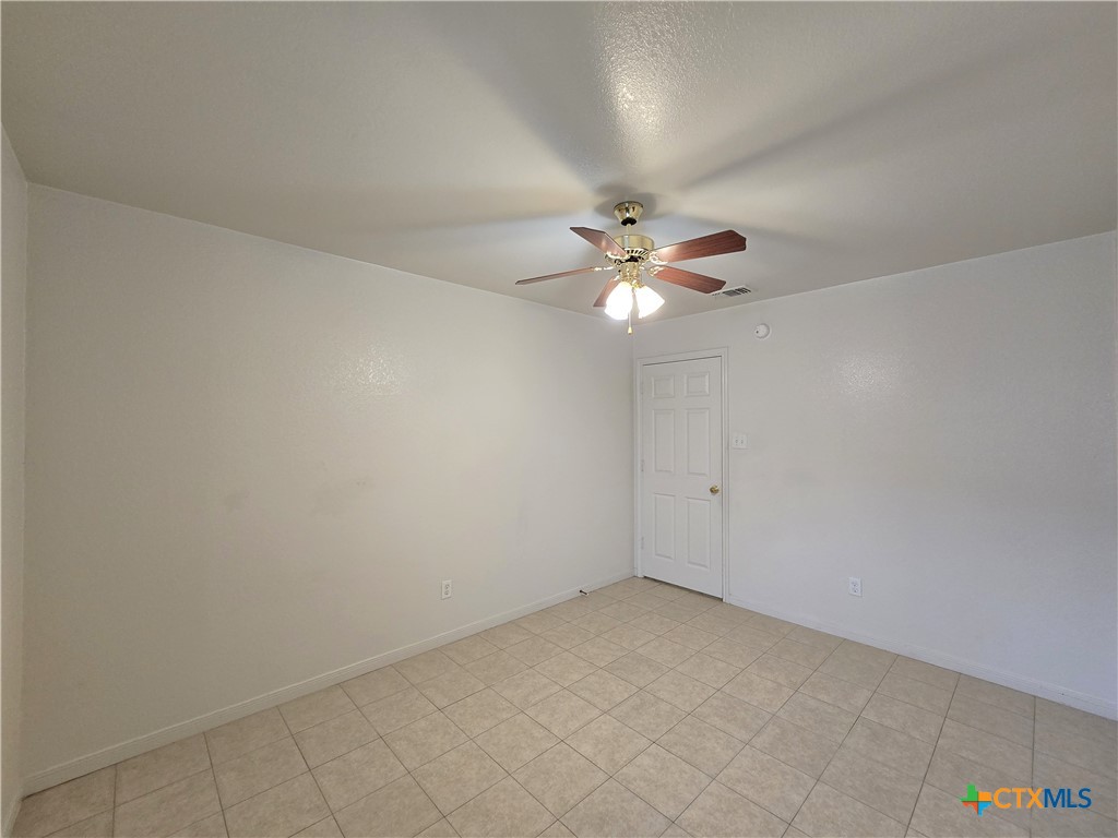 1411 Nicholas Circle, Unit B Killeen, TX 76542 - Photo 22 of 23 an empty room with a chandelier fan and windows