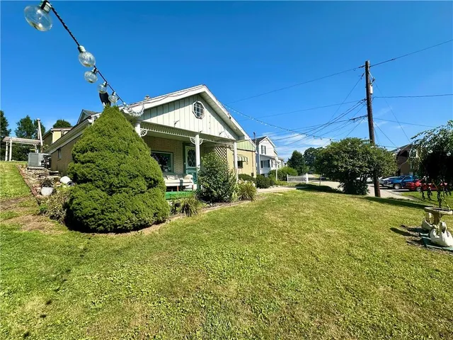 a view of a house with a backyard and a tree