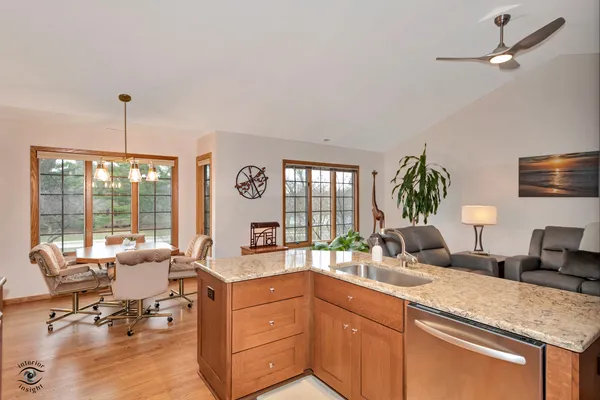a view of a kitchen with kitchen island a large window cabinets a sink and stainless steel appliances