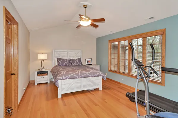 a bedroom with a bed and a large window with wooden floor