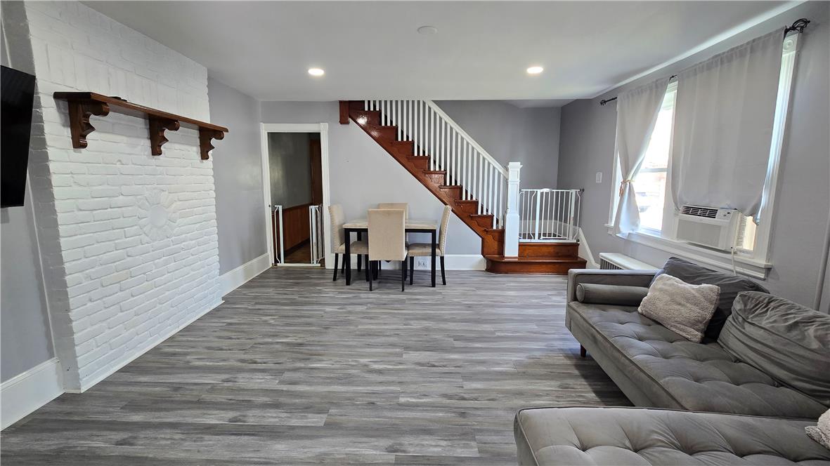 883 North Locust Street Hazleton, PA 18201 - Photo 13 of 83 Well-lit living area features robust flooring, a decorative brick fireplace, and direct access to a staircase.