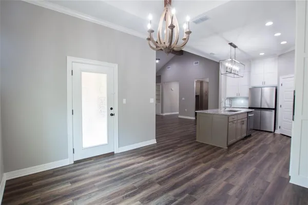 a large kitchen with a refrigerator a stove and a wooden floors