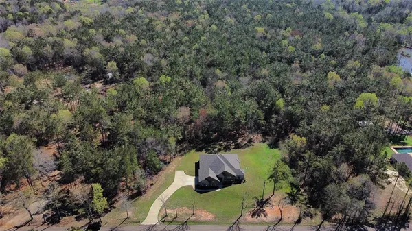 an aerial view of a house with a yard and large trees