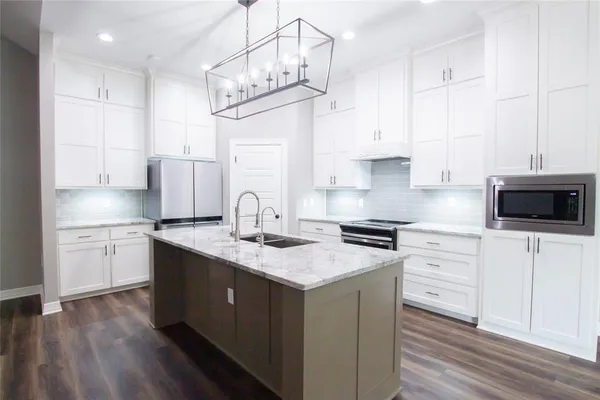 a kitchen with kitchen island granite countertop a sink a stove a oven a counter space and cabinets