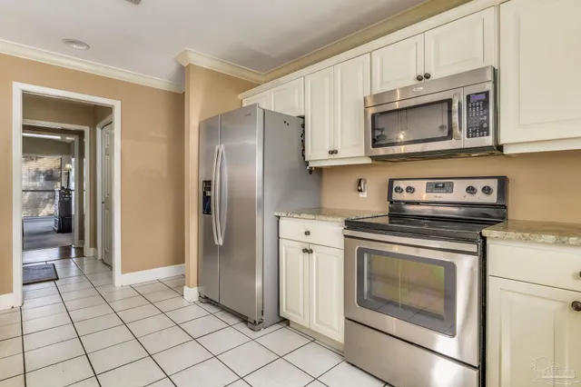 a large kitchen with granite countertop white cabinets and stainless steel appliances