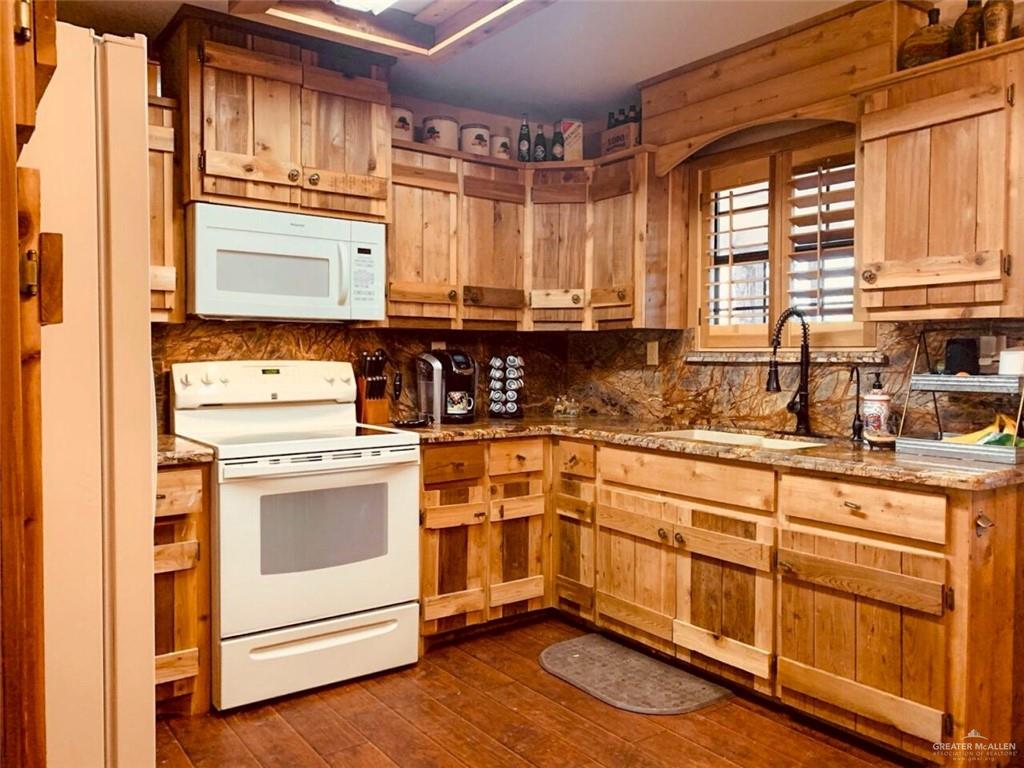 2938 Highway 83 Roma, TX 78584 - Photo 6 of 23 Kitchen with white appliances, dark wood-style flooring, tasteful backsplash, and light stone countertops