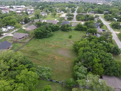 an aerial view of residential houses with outdoor space and trees
