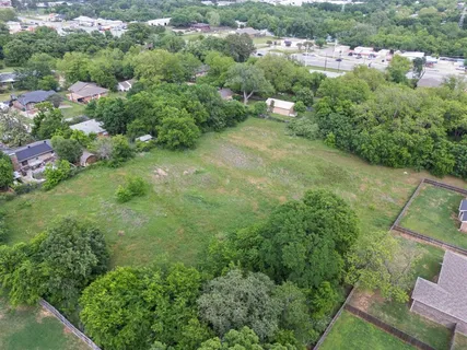 an aerial view of residential houses with outdoor space and trees