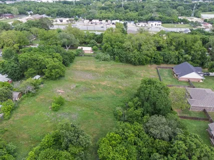 an aerial view of residential houses with outdoor space and trees
