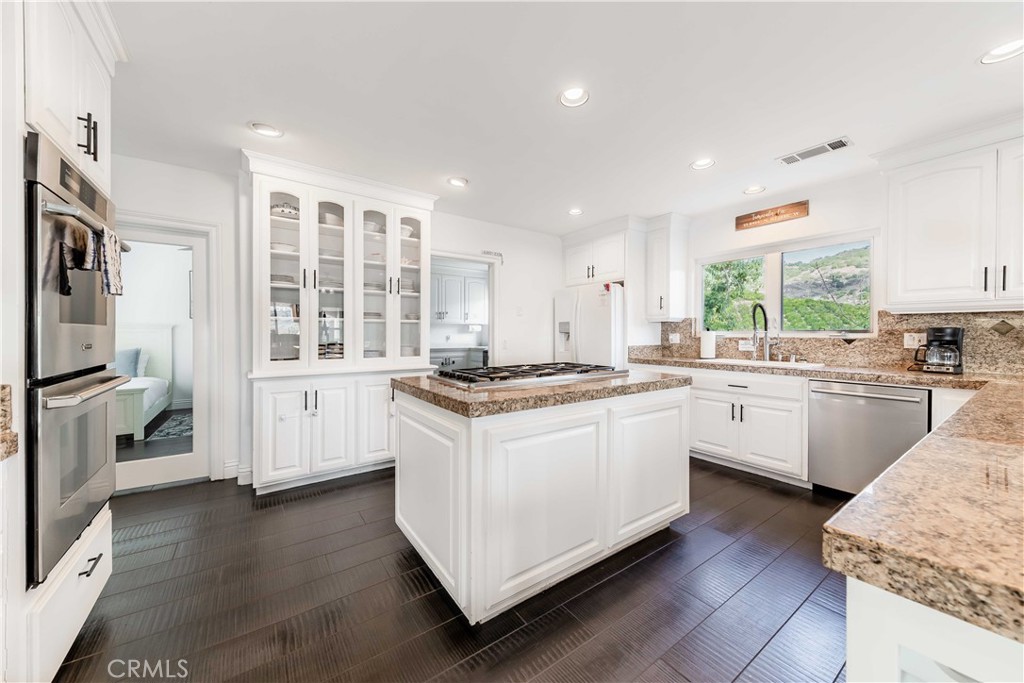 20491 Carancho Road Temecula, CA 92590 - Photo 14 of 64 a kitchen with granite countertop white cabinets and white appliances