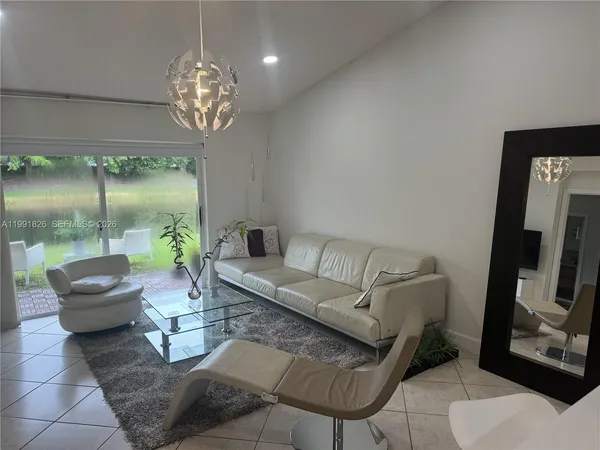 a living room with furniture a chandelier and a flat screen tv