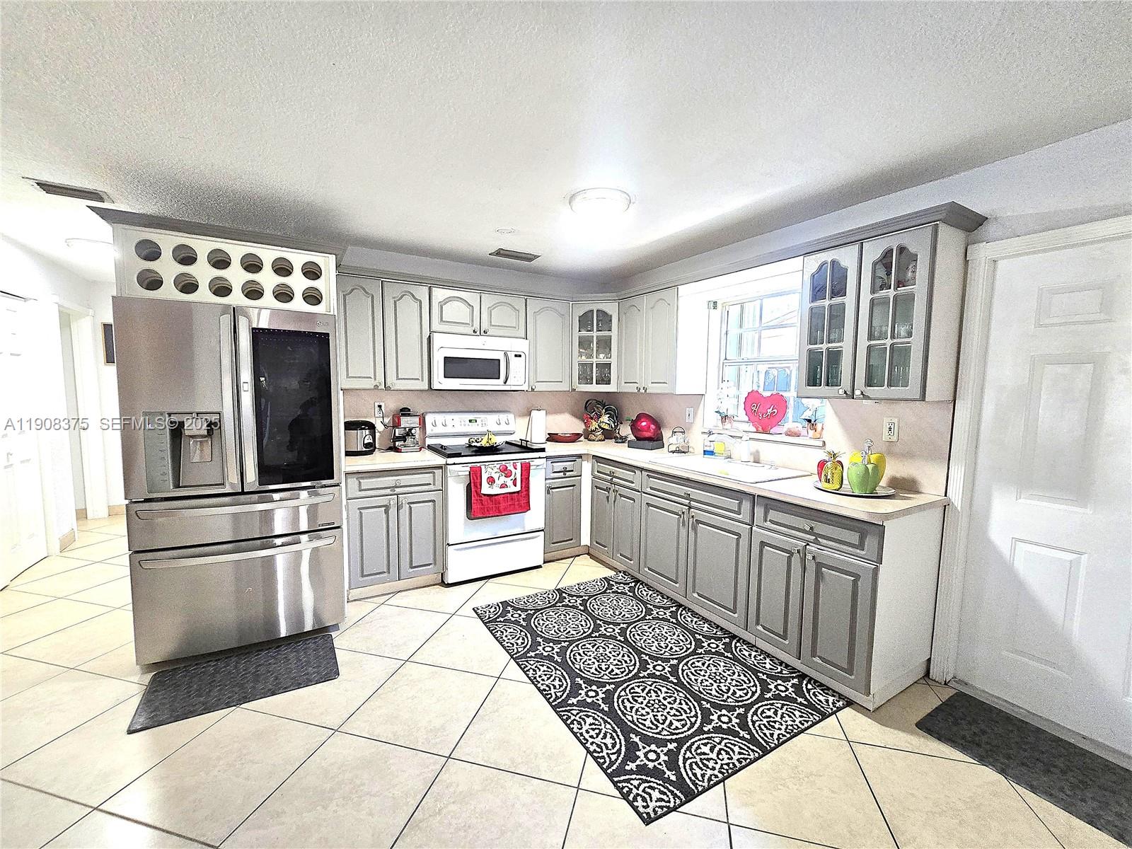 11152 Southwest 7th Street Sweetwater, FL 33174 - Photo 13 of 53 a kitchen with stainless steel appliances kitchen island granite countertop a refrigerator and a stove top oven