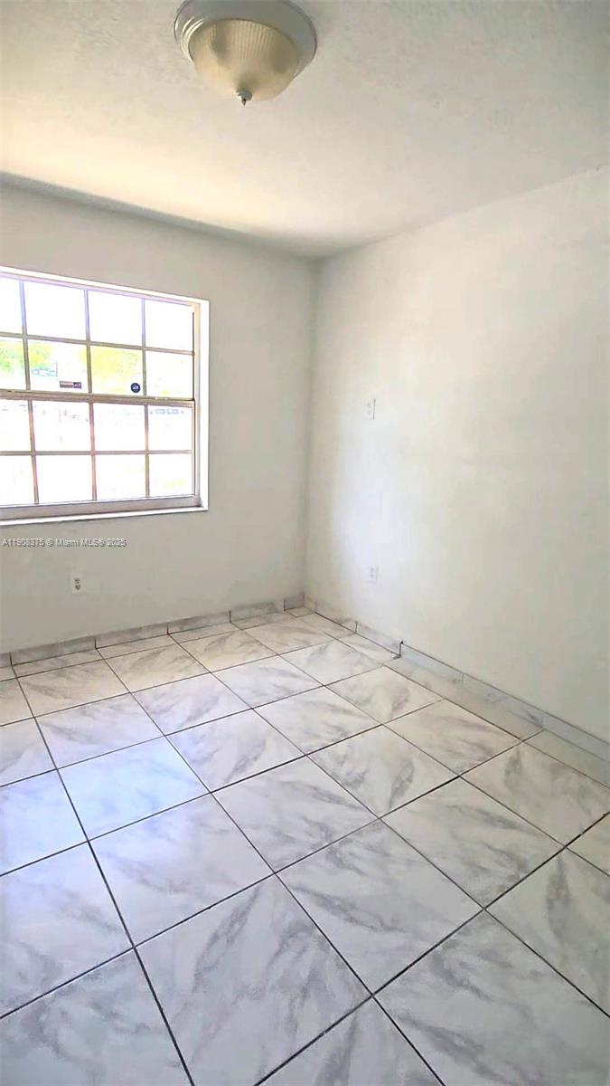 11152 Southwest 7th Street Sweetwater, FL 33174 - Photo 46 of 52 an empty room with a white floor and a window