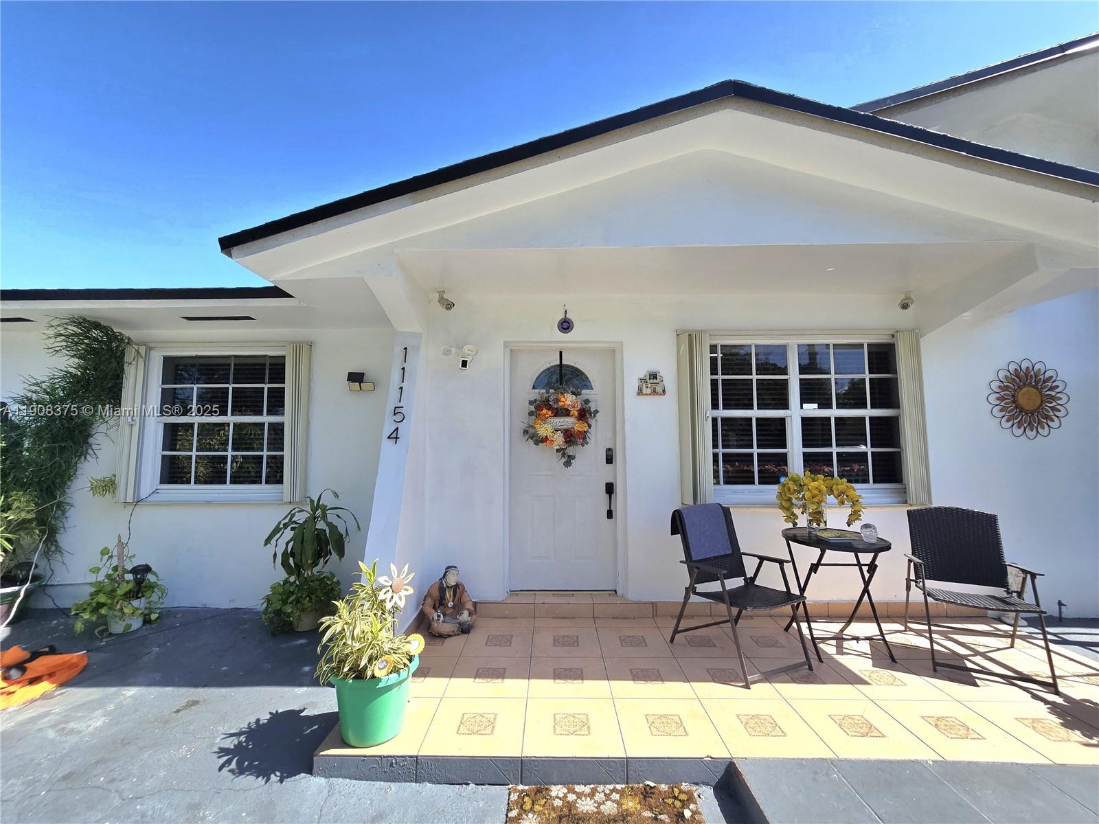 11152 Southwest 7th Street Sweetwater, FL 33174 - Photo 7 of 52 a view of a patio with table and chairs potted plants and floor to ceiling window