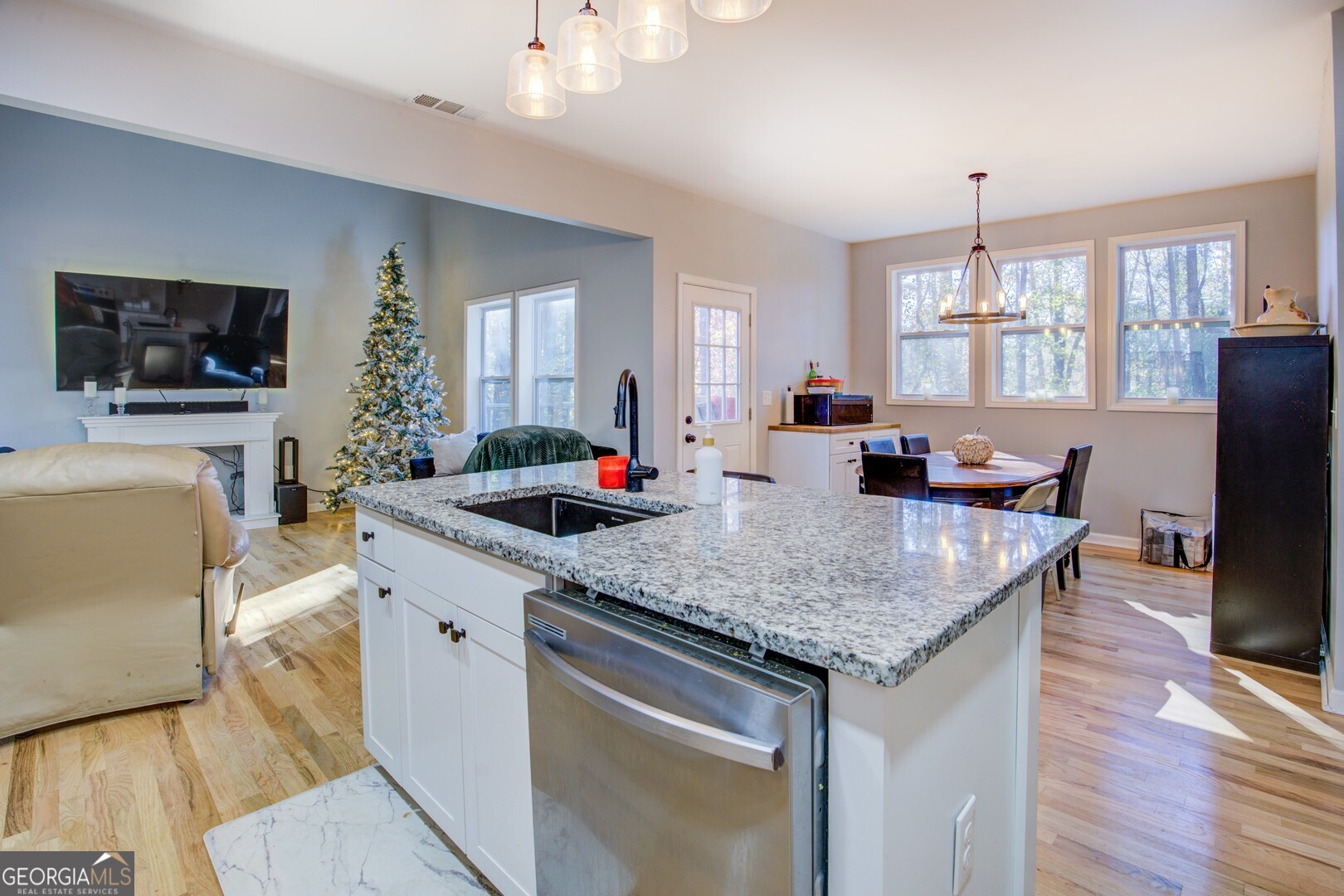13 Goldfinch Circle Monticello, GA 31064 - Photo 22 of 44 a kitchen with granite countertop a sink dishwasher a dining table and chairs with wooden floor